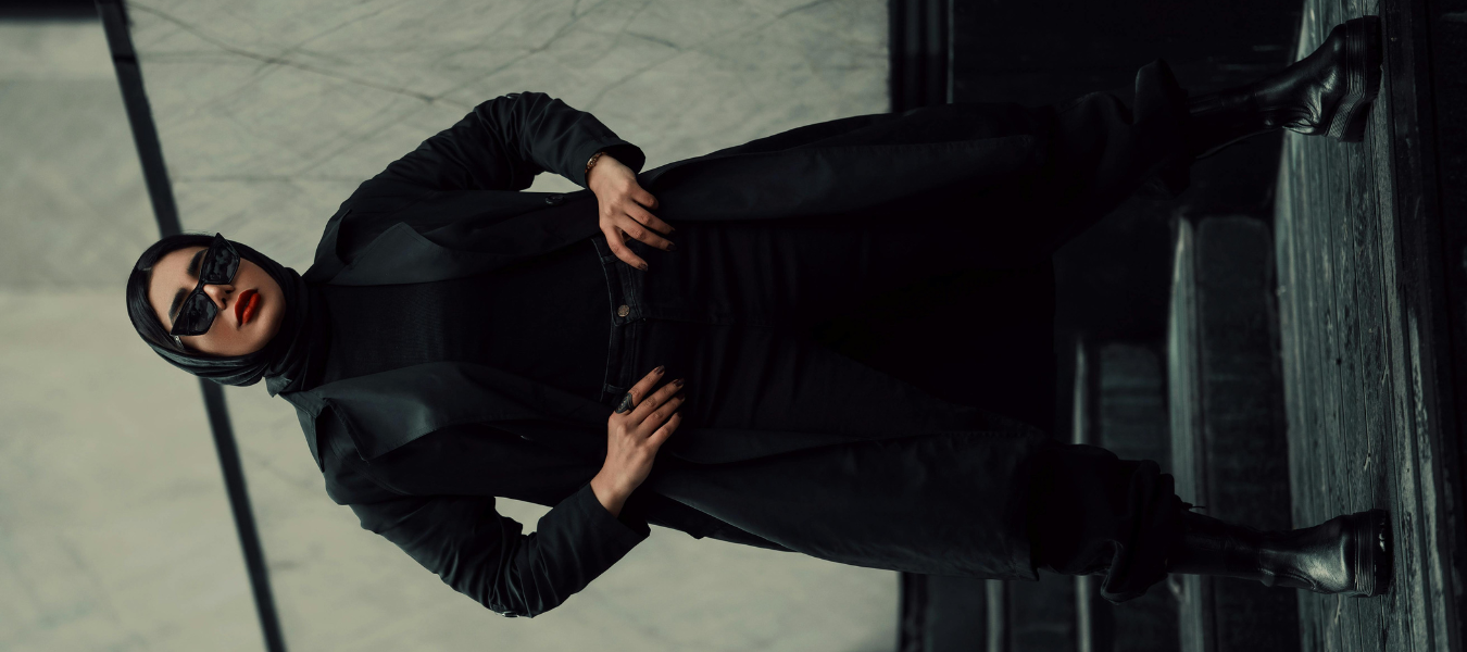 Stylizacja all black – kobieta w długim płaszczu, spodniach i botkach na obcasie, idealne botki do sukienki i spodni