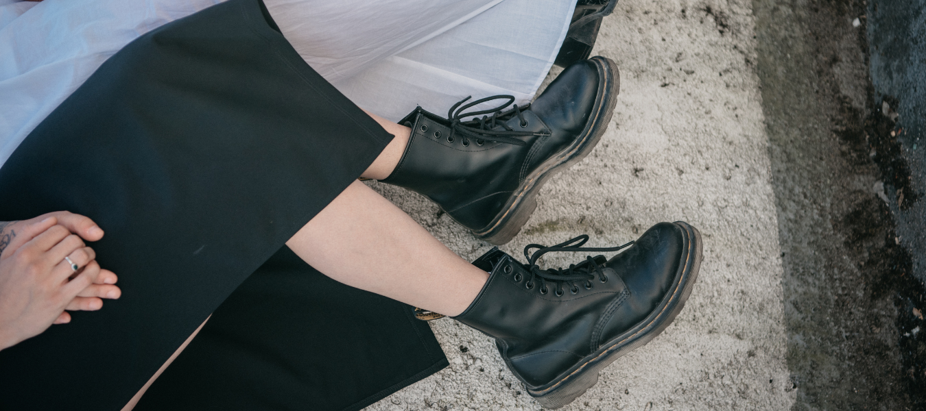 Czarne skórzane glany damskie w jesiennej stylizacji z sukienką midi – modne buty na jesień 2025