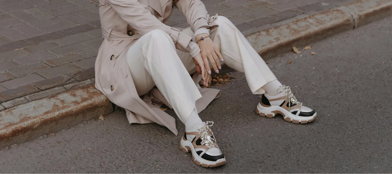 Trendy obuwnicze influencerek – beżowy trencz, jasne spodnie i modne sneakersy na platformie w miejskiej stylizacji na jesień 2025
