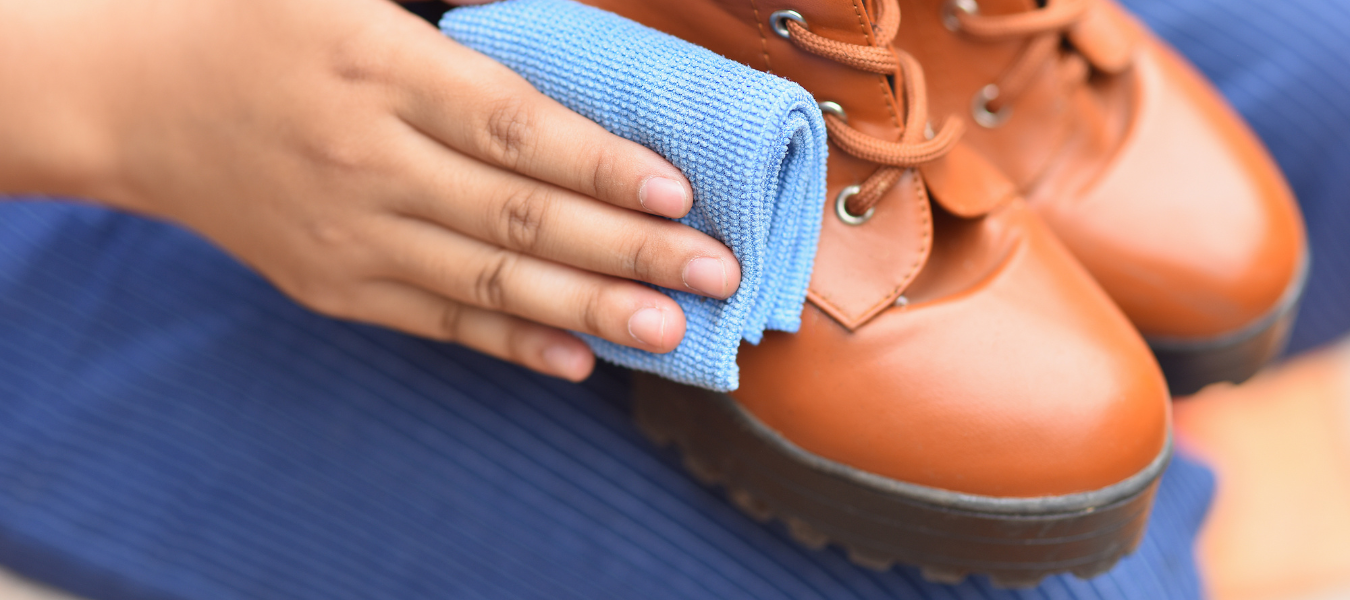 Pielęgnacja butów z ekoskóry – ręczne czyszczenie brązowych butów trekkingowych miękką ściereczką z mikrofibry