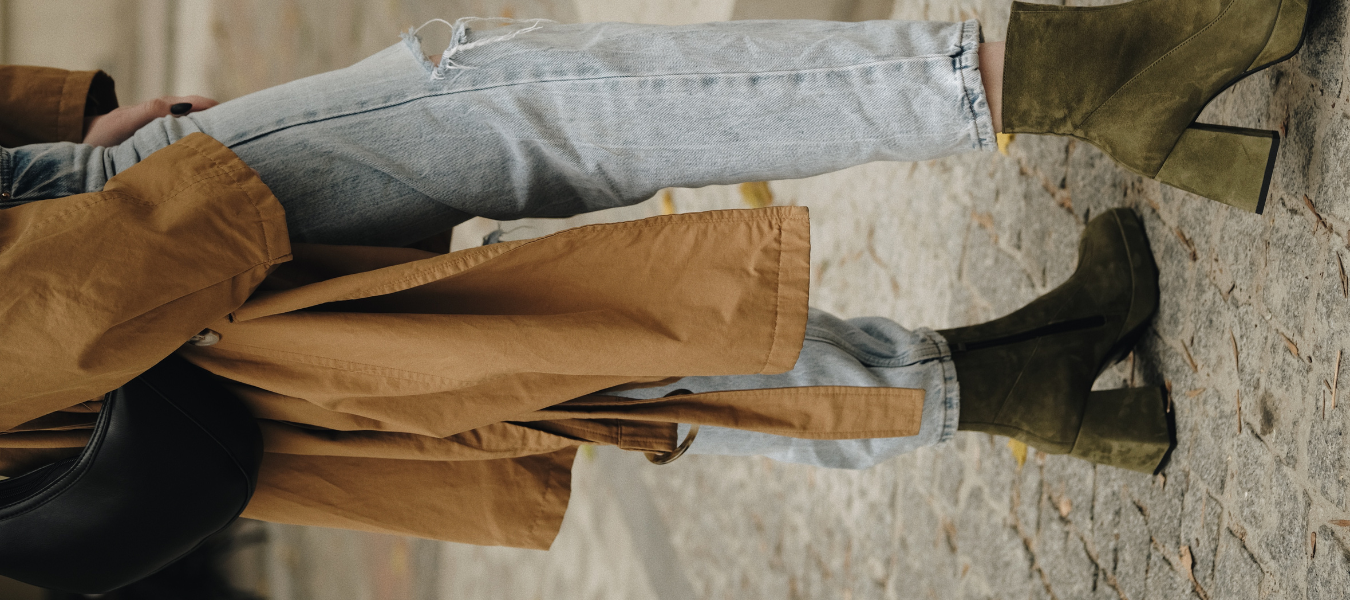 Stylizacja na jesień – oliwkowe botki na słupku, jasne jeansy i beżowy płaszcz damski z czarną torebką