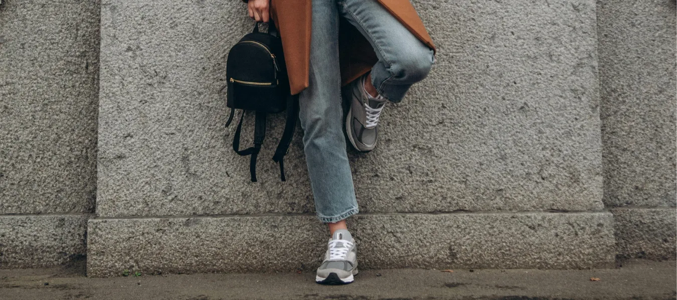 Szare wygodne sneakersy na jesień zestawione z jeansami i camelowym płaszczem - propozycja stylizacji