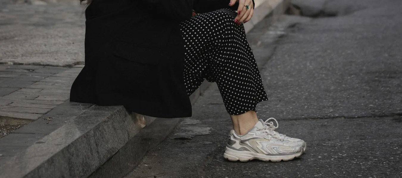 Białe sneakersy damskie w stylizacji z czarnymi spodniami w grochy