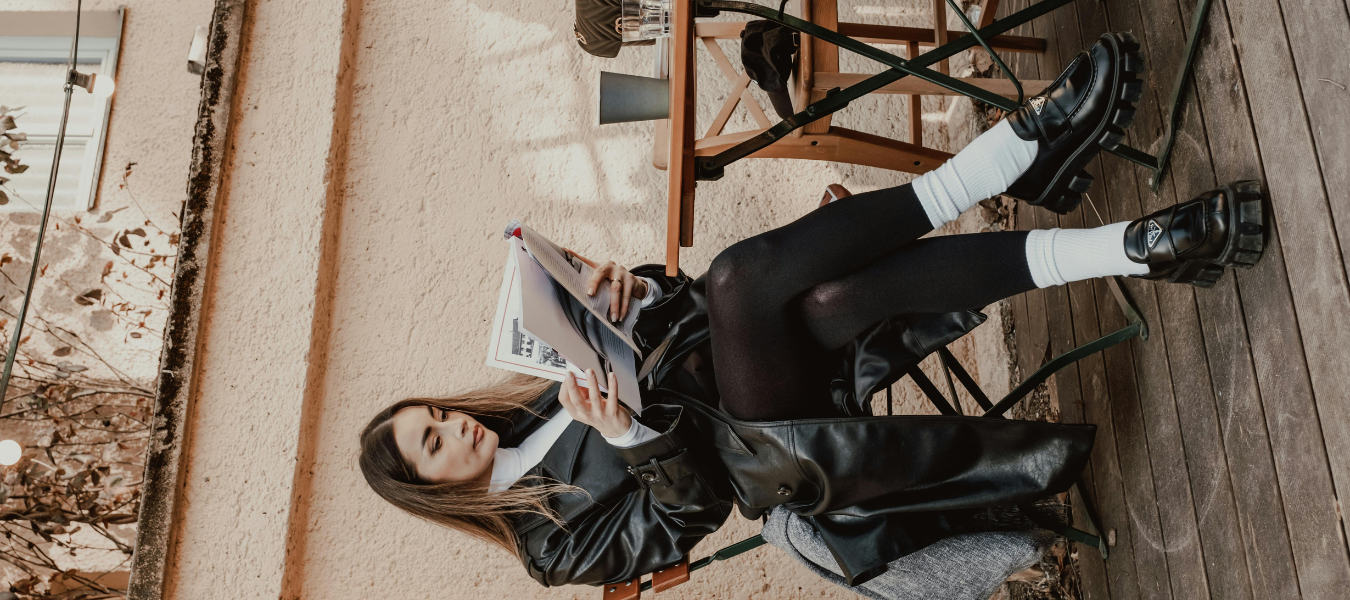 Kobieta w modnej stylizacji z loafersami – czarne mokasyny na grubej podeszwie zestawione z białymi skarpetkami, rajstopami i długim płaszczem