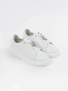 White leather sneakers with a pin by Sergio Leone