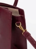 Burgundy handbag with decorative buckle in gold color